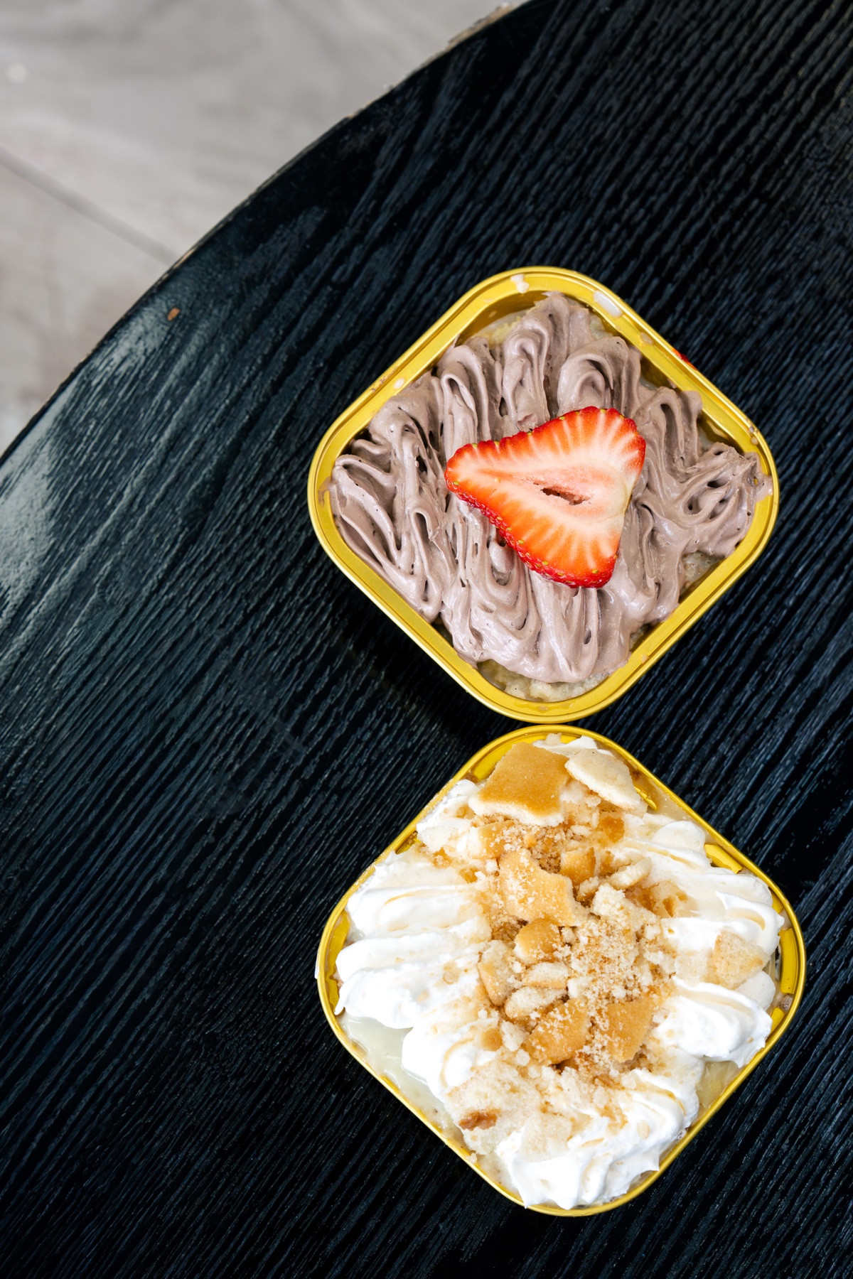 Two tres leches desserts topped with chocolate cream and vanilla cookies